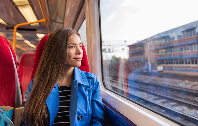 Frau schaut aus einem Bahnfenster nach draußen