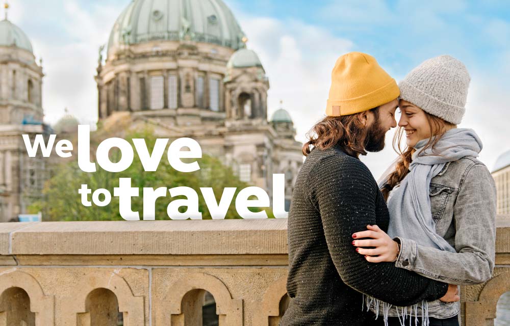 Paar küssend vor Stadtkulisse und Schrift We love to travel