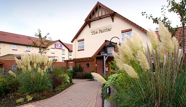 Exterior of Premier Inn Grantham showing restaurant and surrounding greenery