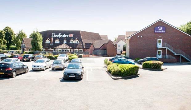 Car park and exterior of Premier Inn Tamworth Central showing cars and Beefeater sign